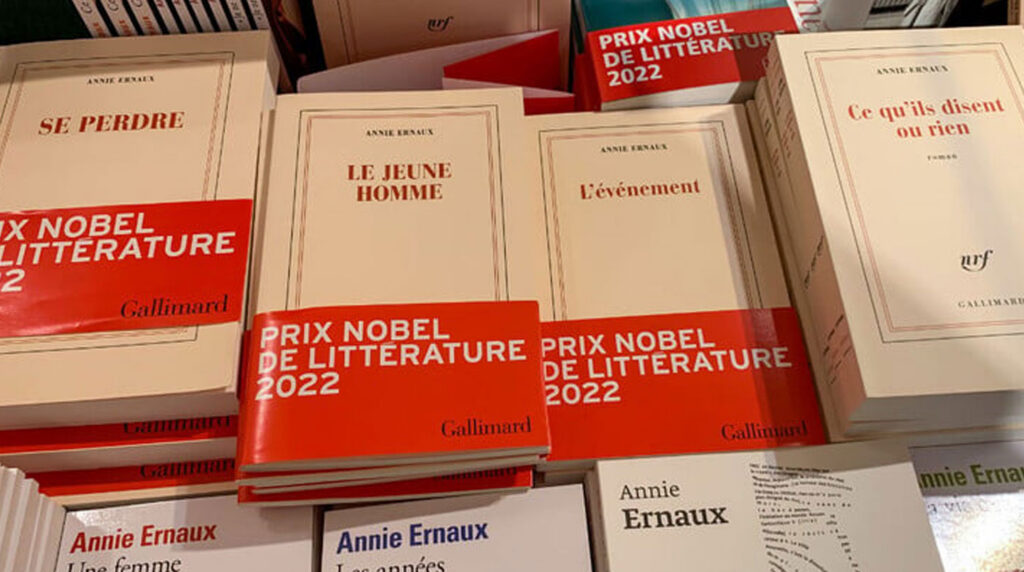 Rayon de librairie contemporaine française avec éditions de Camus (Pléiade et Folio) sur étagères en bois clair et métal, lumière naturelle abondante Rayon de librairie contemporaine française avec éditions de Camus (Pléiade et Folio) sur étagères en bois clair et métal, lumière naturelle abondante